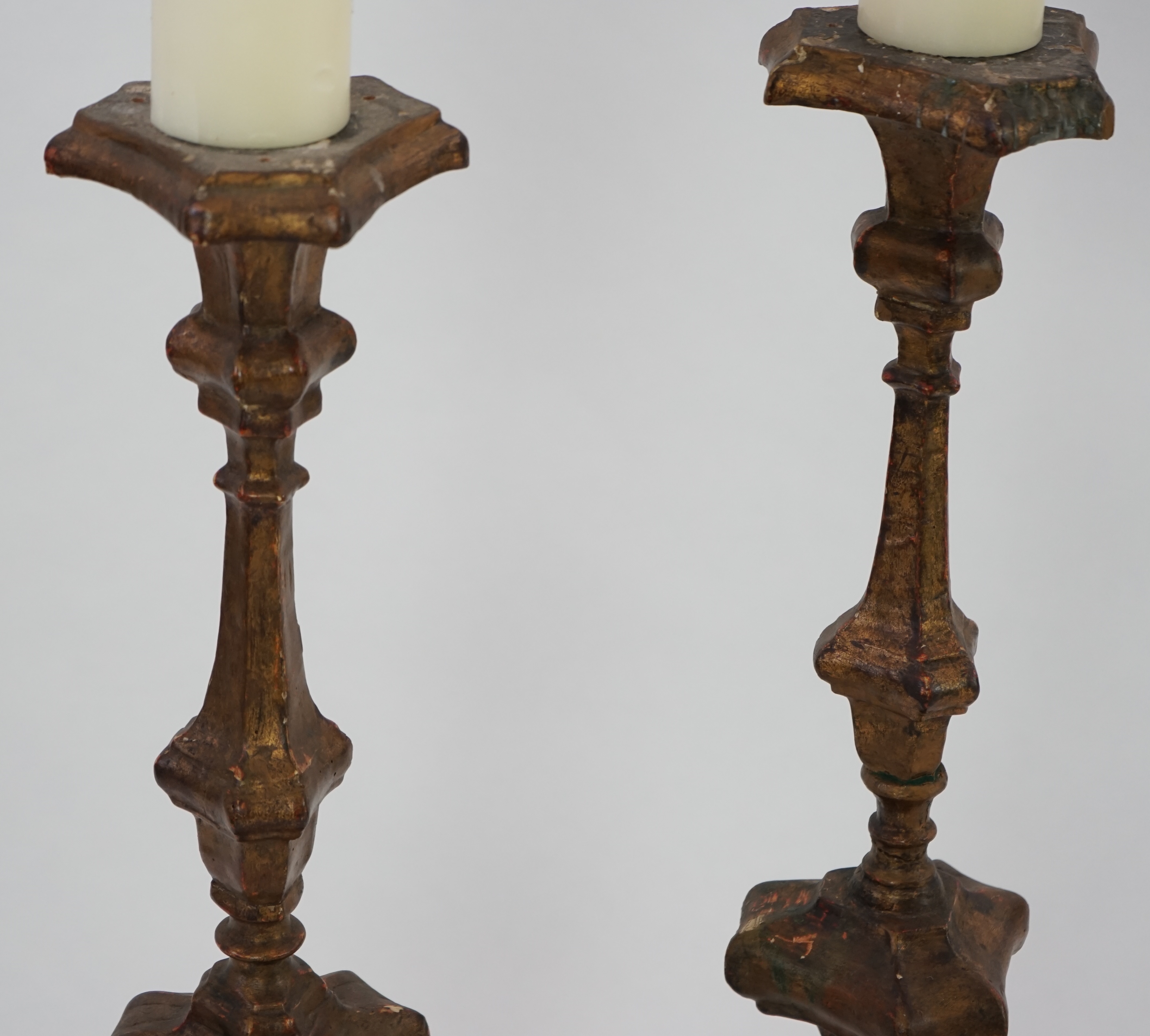 A pair of 18th century Italian giltwood candlesticks with knopped triangular stems and scroll feet, 89cm high. Condition - fair, Provenance- Brede Place, East Sussex, a former residence of the Frewen family from 1712-193